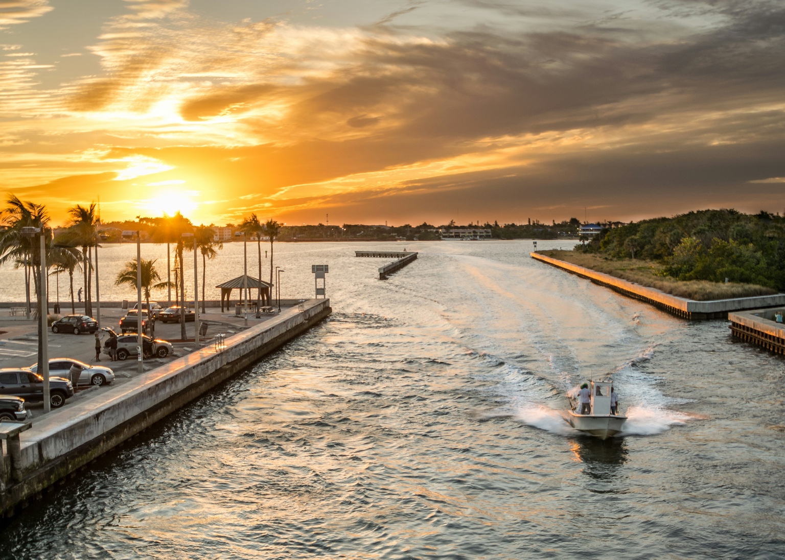 Florida waterfront at sunset with palm trees and a boat